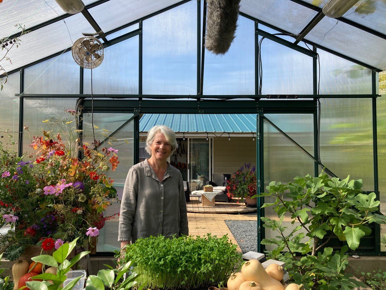 Donna Balzer in her thriving Pacific BC Greenhouse featuring butternut squash and greens