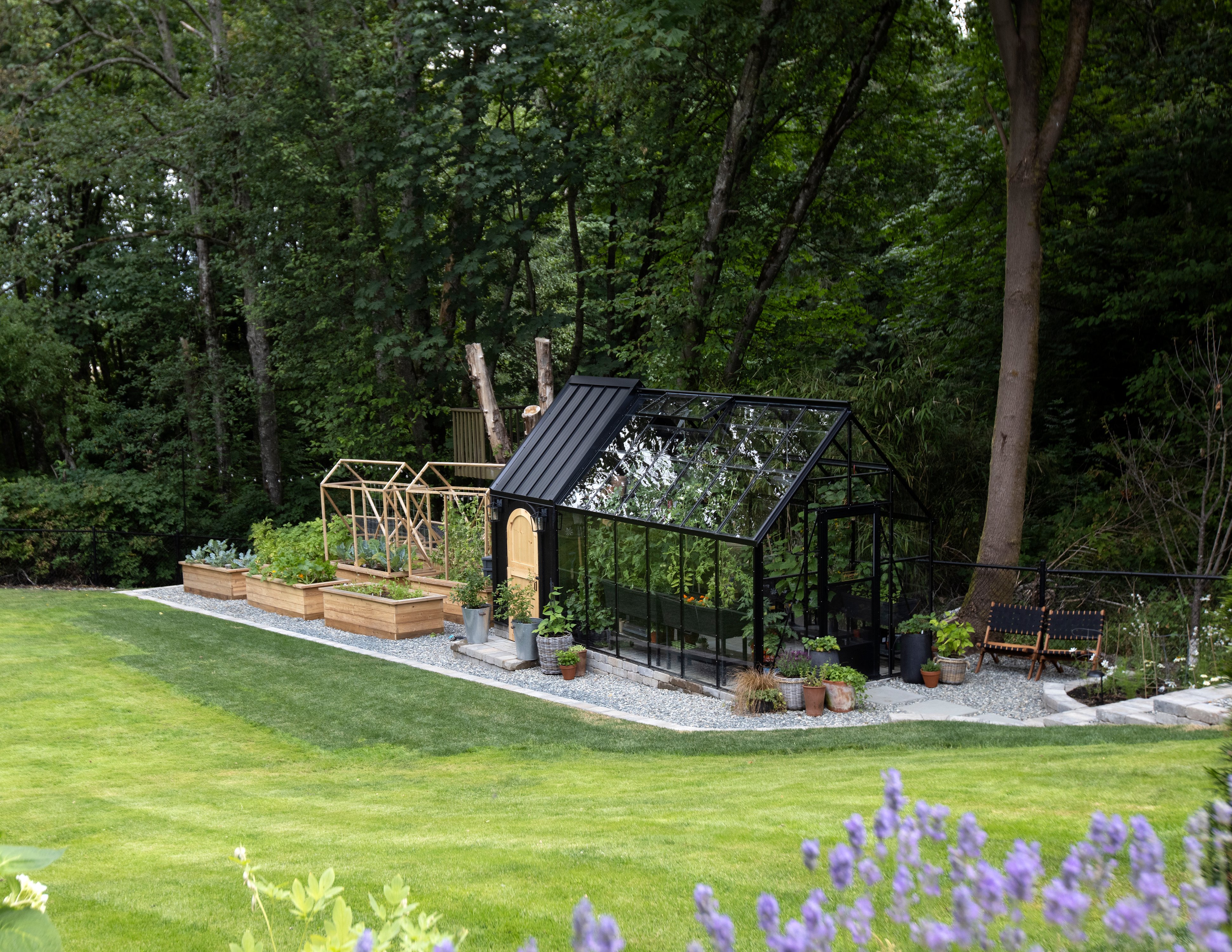 Black greenhouse attached to chicken coop in garden